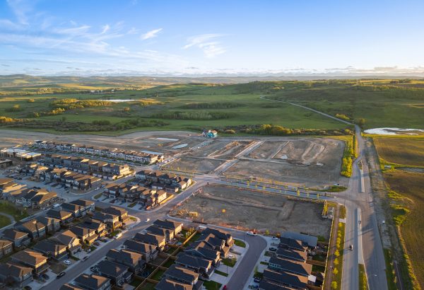 Aerial sunset photo of the community of Sirocco in Southwest Calgary featuring foothills, a golf course and new home construction.